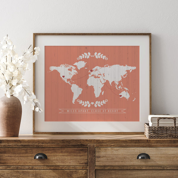 Framed personalized world map art set on a rustic wooden table with decorative home accessories
