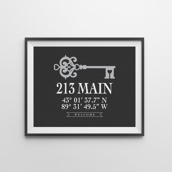Framed custom housewarming gift wall art hanging in a modern hallway, featuring a home address and coordinates.